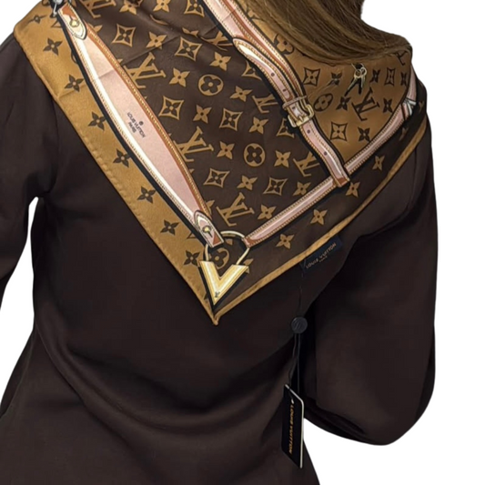Close-up detail of the classic brown monogram print silk scarf showing intricate graphics of chains, straps, and gold padlock motifs with pastel pink borders.