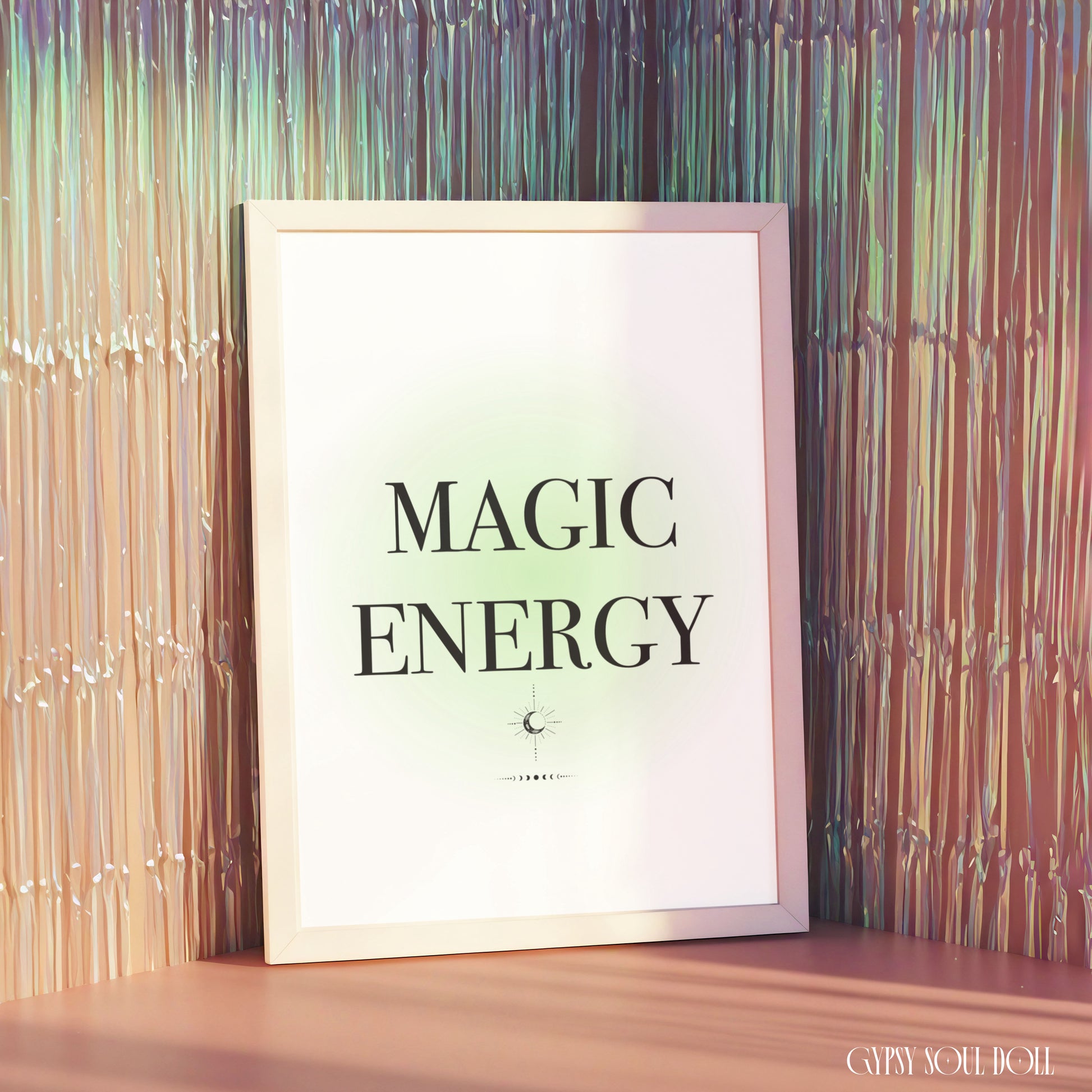 Minimalist green gradient aura typography print reading Magic Energy in a white frame displayed against a shimmering metallic fringe backdrop.