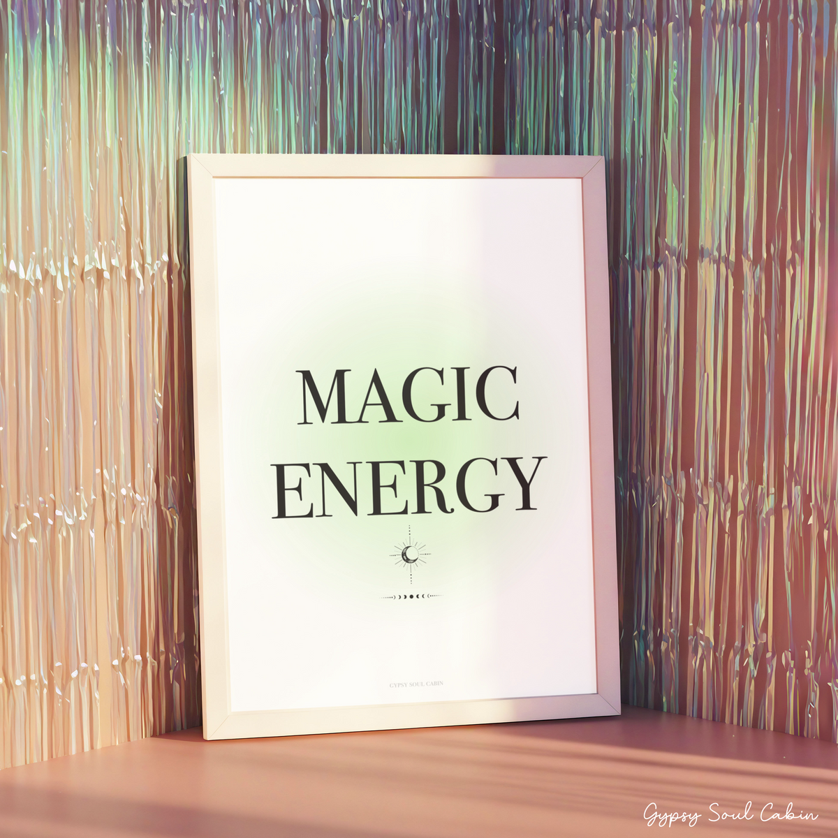 Minimalist green gradient aura typography print reading Magic Energy in a white frame displayed against a shimmering metallic fringe backdrop.