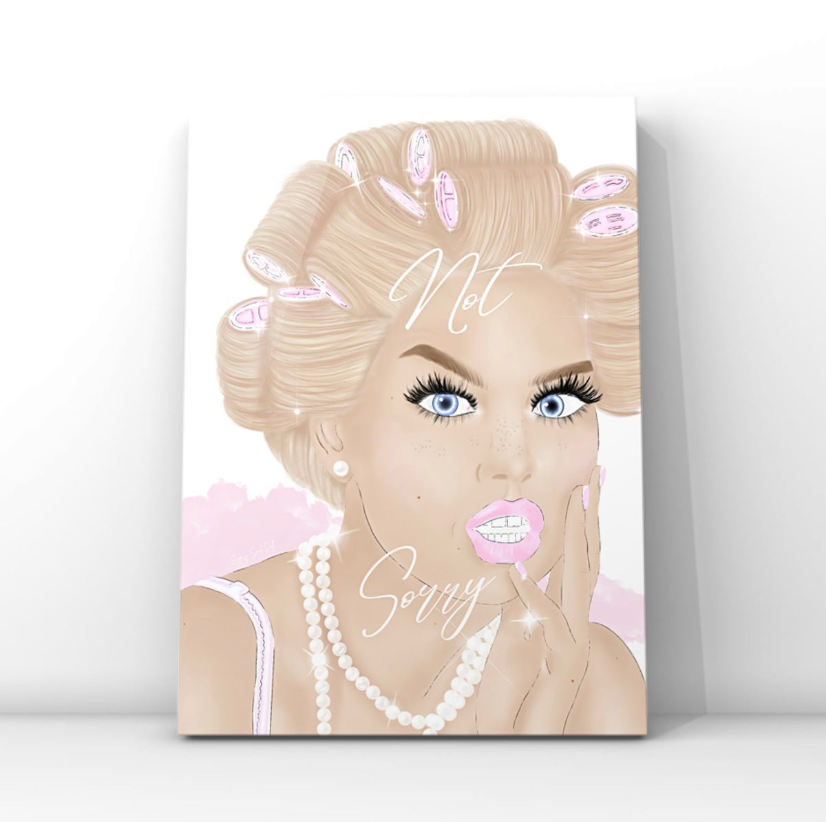 A vertical wall art print featuring a stylised illustration of a blonde woman with pink hair curlers, blue eyes, long lashes and a white pearl necklace, with the text 'Not Sorry' written across the portrait by Gypsy Soul Doll. The glam print is shown leaning against a light gray wall on a white surface.