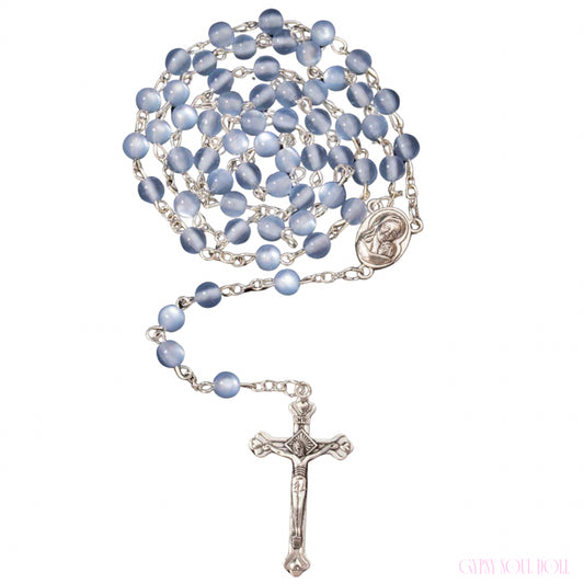 A blue glass bead rosary necklace with a silver-tone crucifix and medallion, displayed on a clean white background.