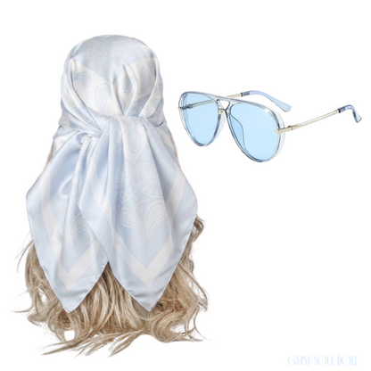 Studio product layout featuring a pastel blue and white paisley printed satin square headscarf tied on a blonde mannequin wig, alongside matching translucent blue fashion sunglasses.
