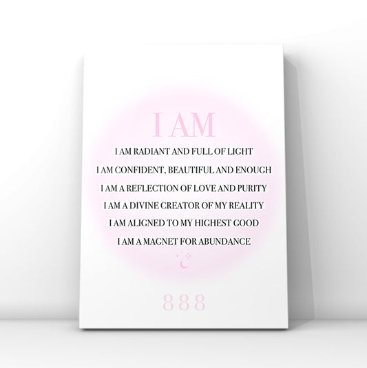 A vertical white art print with a pink circular glow and black text reading 'I AM' followed by affirmational phrases, plus '888' near the bottom, shown leaning against a light gray wall.