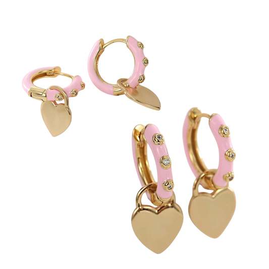 Studio product shot showcasing two pairs of gold-plated brass hooplets coated in pastel pink enamel, studded with small crystals and detailed with dangling heart charms.
