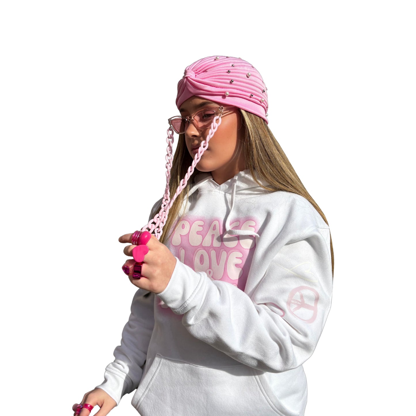 Side view of a model wearing a pink Ibiza head wrap and a white oversized slogan hoodie, with added pink fashion accessories.