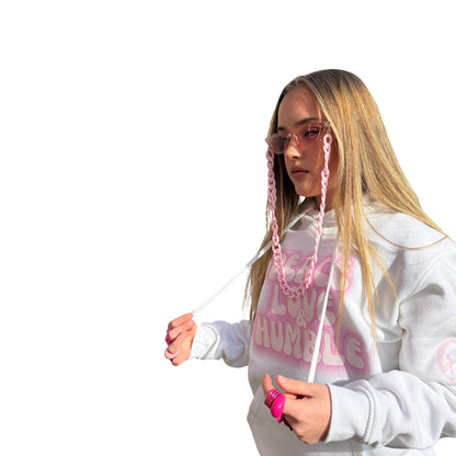 Side angle view of a model in a white oversized graphic hoodie with pink fashion accessories, showing the roomy fit of the sleeve.