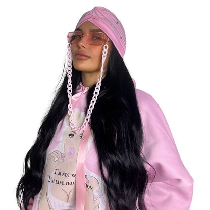 Close-up front view of a model in a pink scrunched sleeve hoodie styled with a matching pink boho Ibiza head wrap and pink fashion glasses attached to a powder pink link chain.