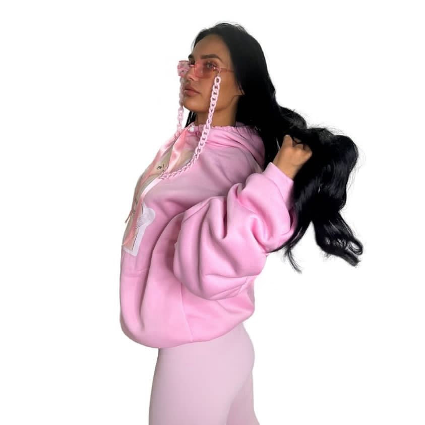 Side view of a model showing the roomy silhouette and custom scrunched sleeve texture of the pink polyester festival hoodie and matching fashion glasses.