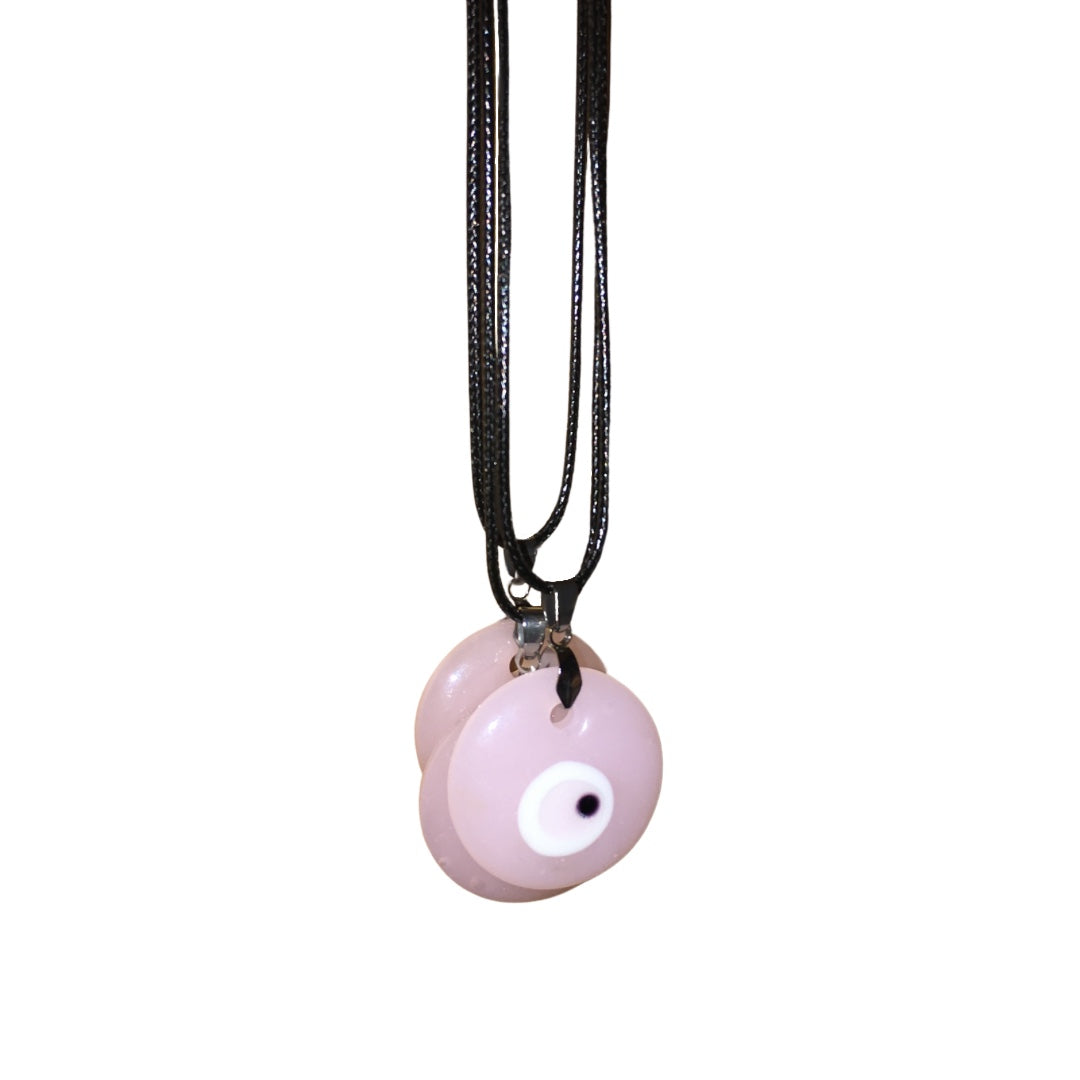 A collection of pink evil eye beads on a black cord necklace, shown against a plain white background.