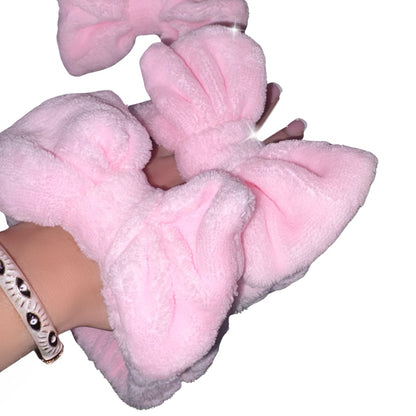 A close-up of a woman's hand with French manicure nails, showcasing fluffy pink bow headbands by Gypsy Soul Doll.