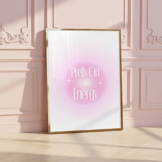A gold framed poster of the Pretty Girl Energy pink aura print leaning against a luxury pink panelled wall in a chic, sunlit bedroom.