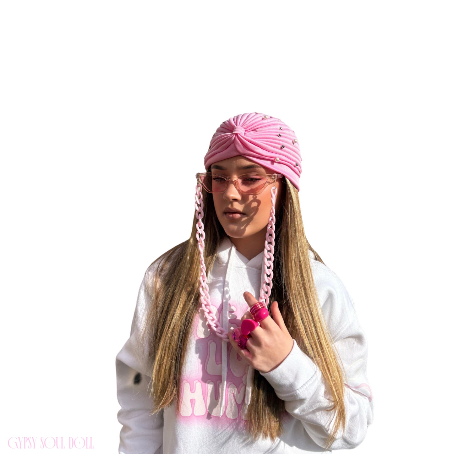 A pretty girl wearing a Gypsy Soul Doll unique hoodie with pink accessories to match such as pink fashion glasses, pink fashion Y2T style rings and gypsy head wrap on a fresh white background.