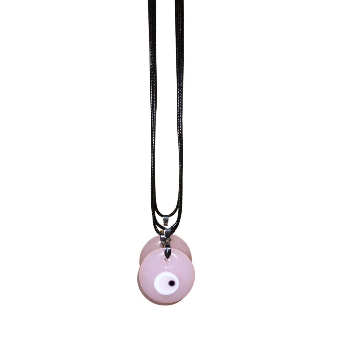 Close-up of a woman with glam makeup wearing a light denim shirt and the soft pastel pink glass evil eye cord necklace.