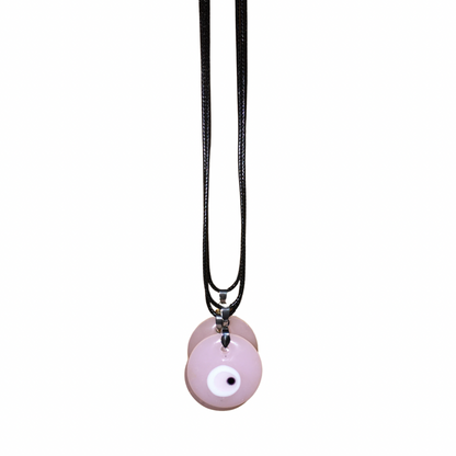 Close-up of a woman with glam makeup wearing a light denim shirt and the soft pastel pink glass evil eye cord necklace.