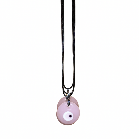Close-up of a woman with glam makeup wearing a light denim shirt and the soft pastel pink glass evil eye cord necklace.