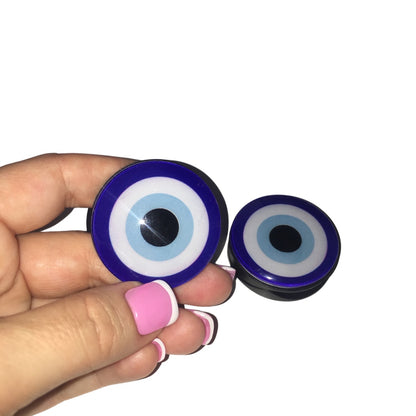 Close-up of a hand holding a rich cobalt blue and light blue circular evil eye phone socket stand against a clean background.