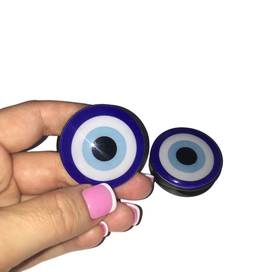Close-up of a hand holding a rich cobalt blue and light blue circular evil eye phone socket stand against a clean background.