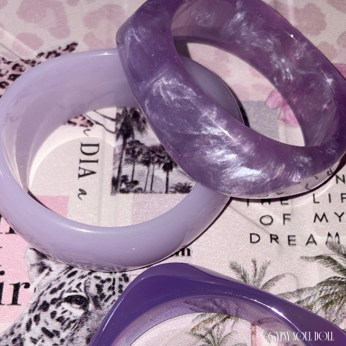 Macro detailed shot highlighting the glossy surfaces, translucent lavender color tones, and white swirling marble textures of the chunky acrylic jewelry stack.