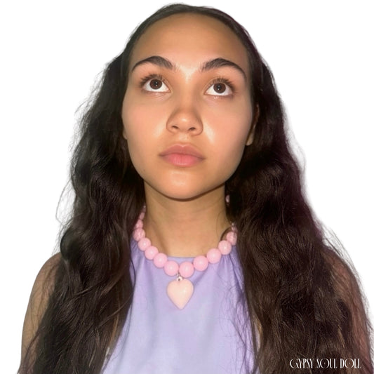 Model showcasing the Gypsy Soul Doll pink chunky bubblegum bead necklace with a large matching pastel pink puffy heart pendant worn with a lilac top.
