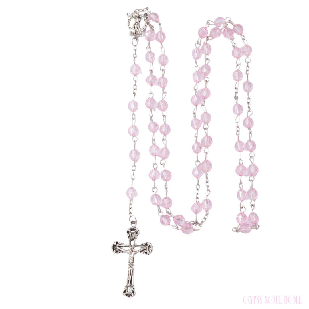 The Gypsy Soul Doll Sweetheart rosary beads feature coiled, transparent, faceted pink crystal beads linked on a silver chain with a crucifix pendant.