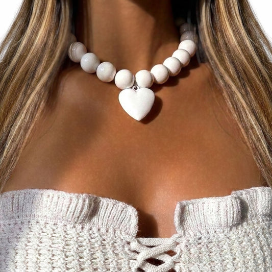 Close-up of a model styling a chunky statement collar choker featuring oversized white glossy beads and a matching polished white heart pendant charm.