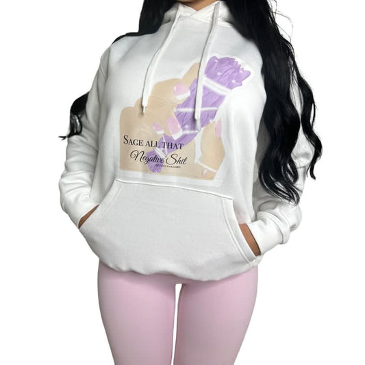 A woman wearing a white pullover hoodie with a graphic print on the front. The graphic features a hand with purple manicured nails and the text 'SAGE ALL THAT Negative Shit'.